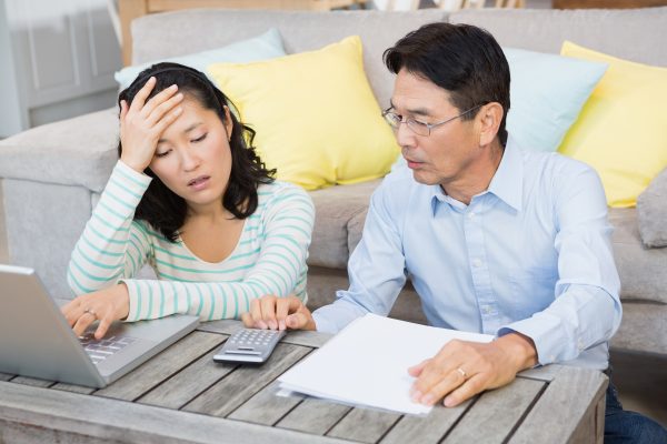 No Surprises Act: Six FAQs about the qualifying payment amount (QPA) 2 worried couple checking bills living room