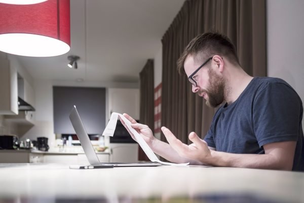 Sorting out the confusion: When the No Surprises Act does—and doesn’t—apply 2 man managing finances sitting near laptop looking receipt being surprise unhappy